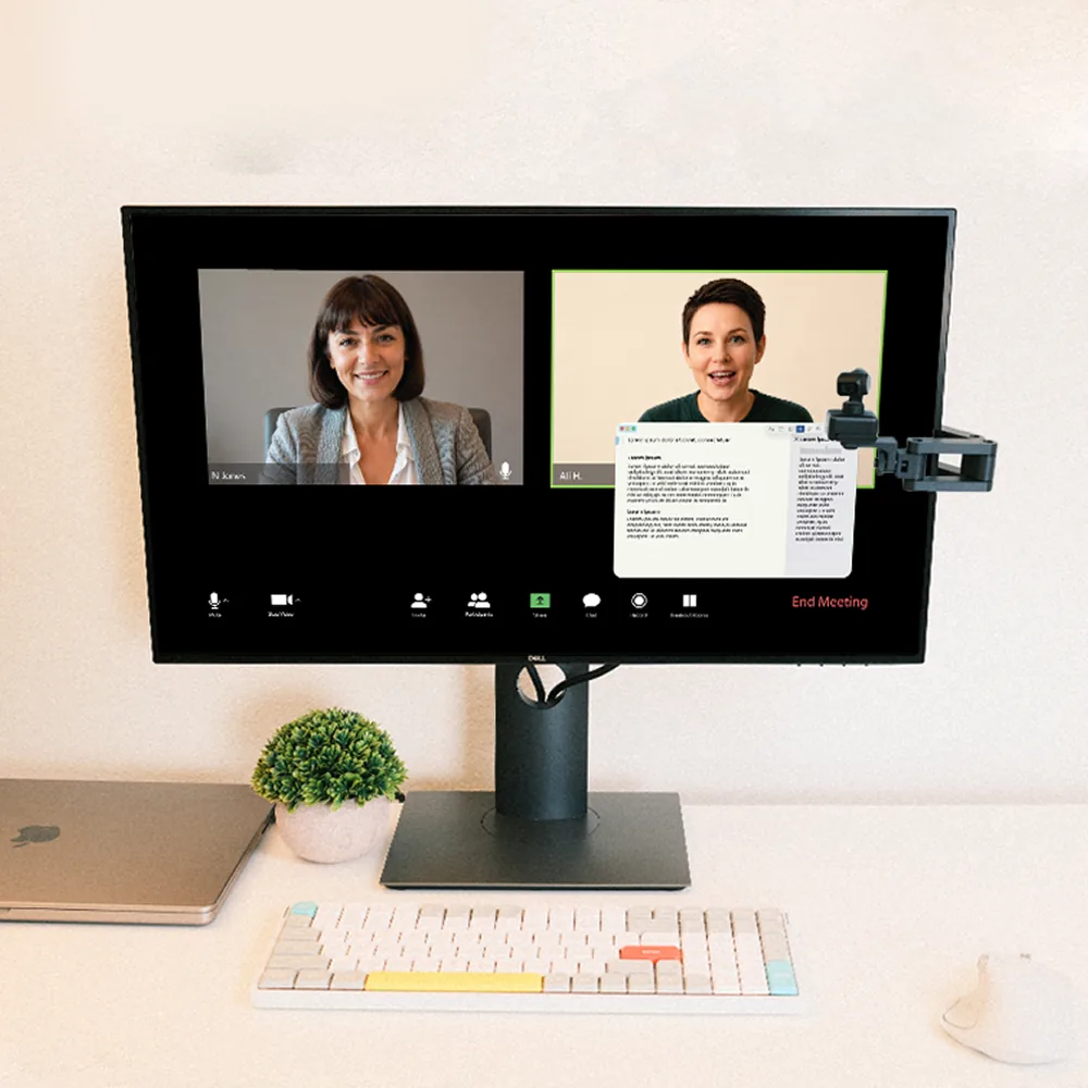 The Calibra arm holding the webcam at eye level beside the monitor, so eye contact lands
