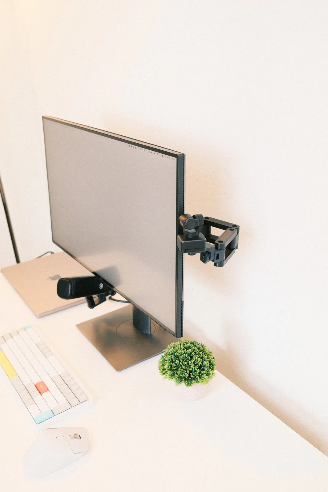 The Calibra arm holding a webcam at eye level beside a monitor on a clean desk